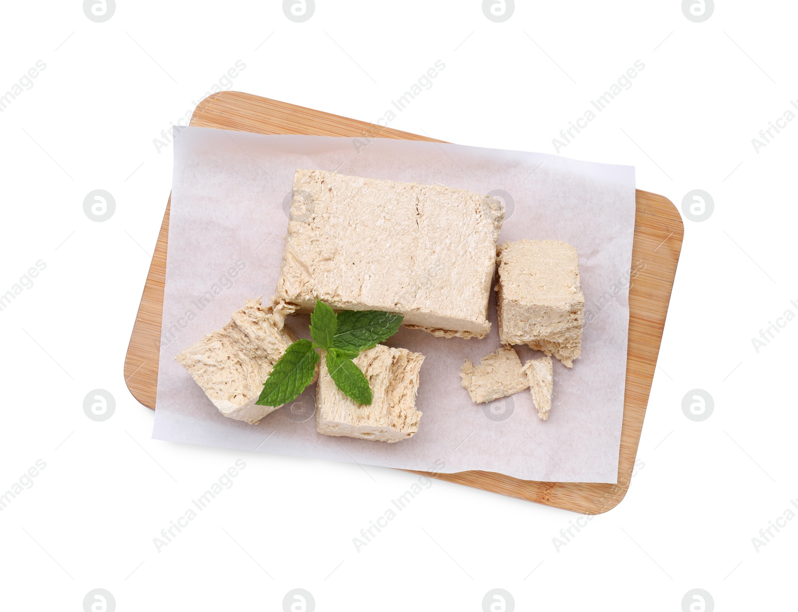 Photo of Board with pieces of tasty halva and mint isolated on white, top view