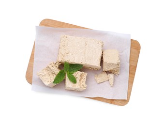 Photo of Board with pieces of tasty halva and mint isolated on white, top view