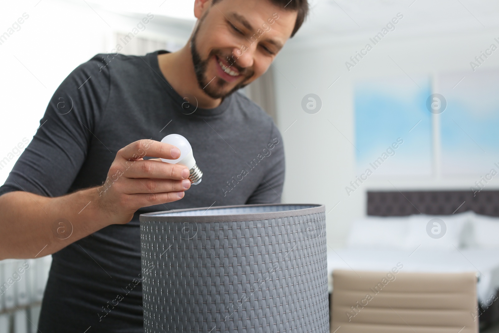 Photo of Man changing light bulb in lamp indoors