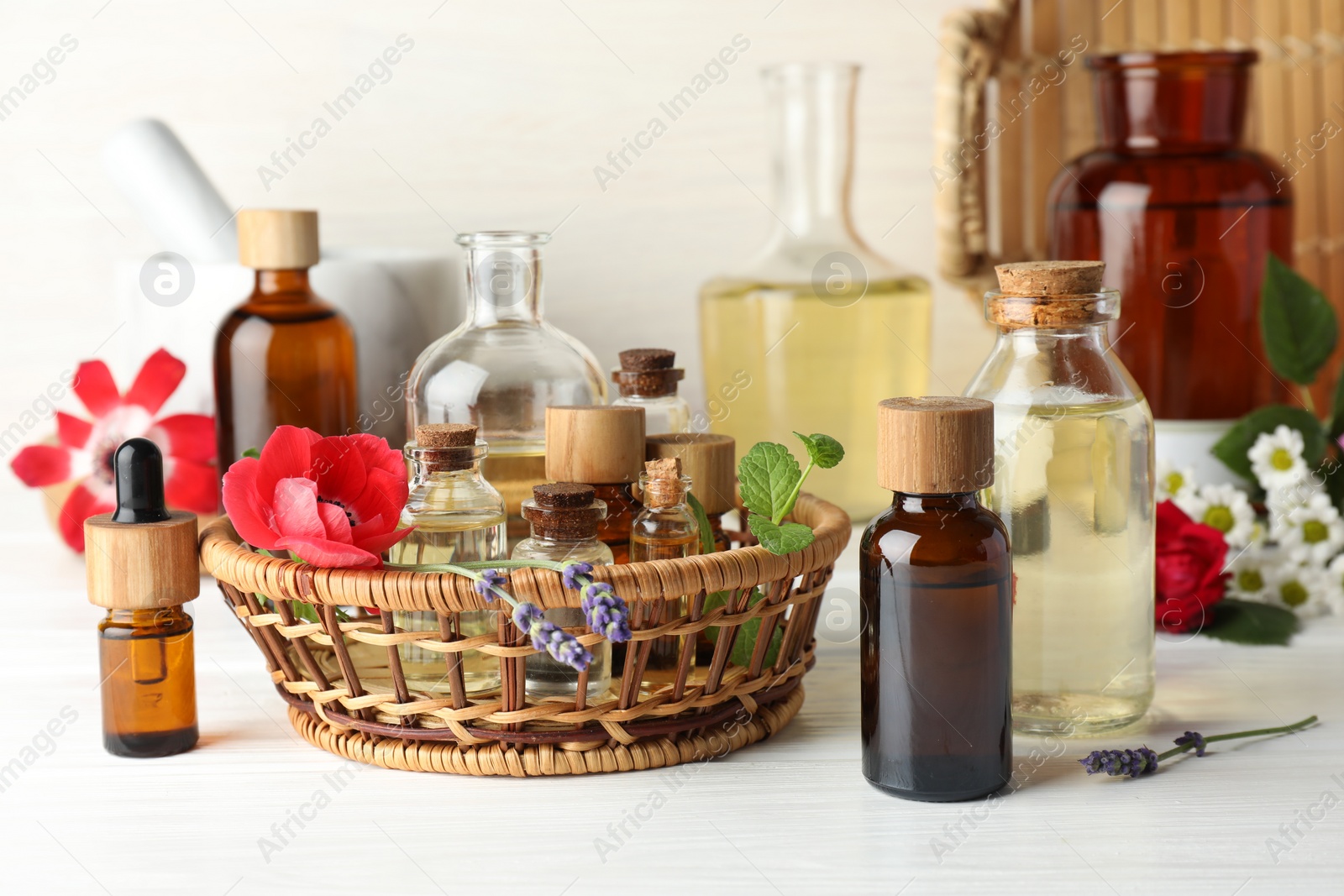 Photo of Aromatherapy. Different essential oils and flowers on white wooden table