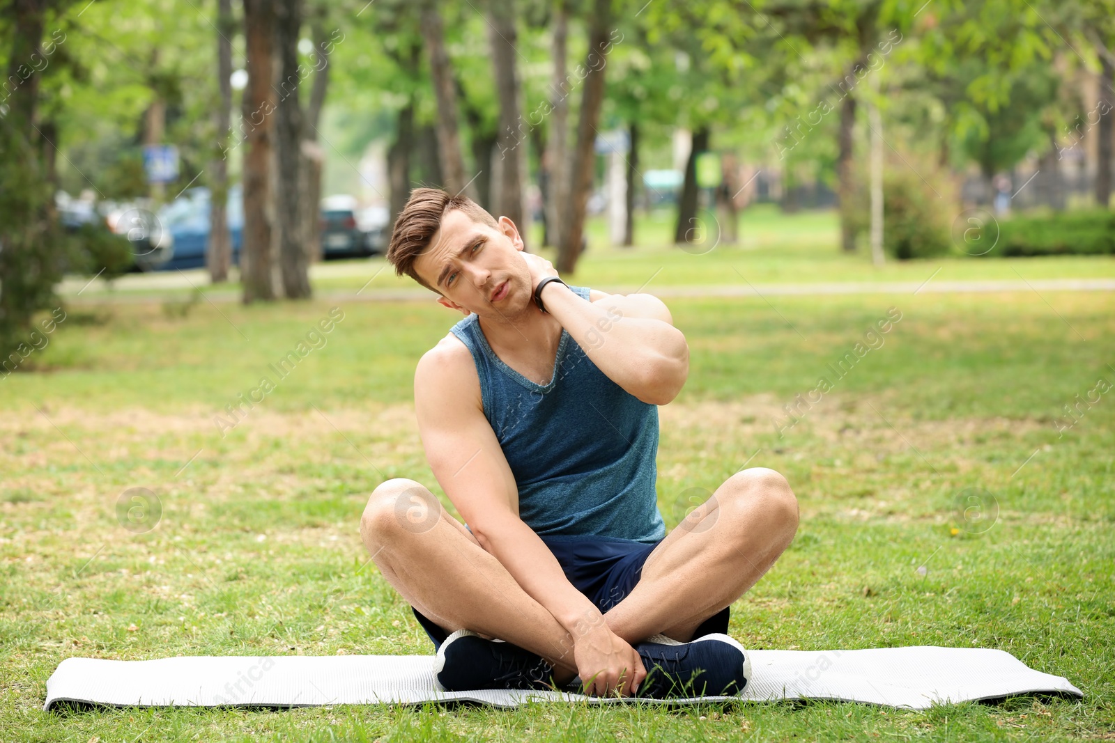 Photo of Male athlete suffering from neck pain during training outdoors