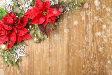 Flat lay composition with traditional Christmas poinsettia flowers and space for text on wooden table. Snowfall effect