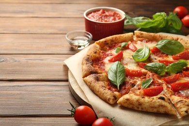 Photo of Delicious Margherita pizza and ingredients on wooden table, space for text