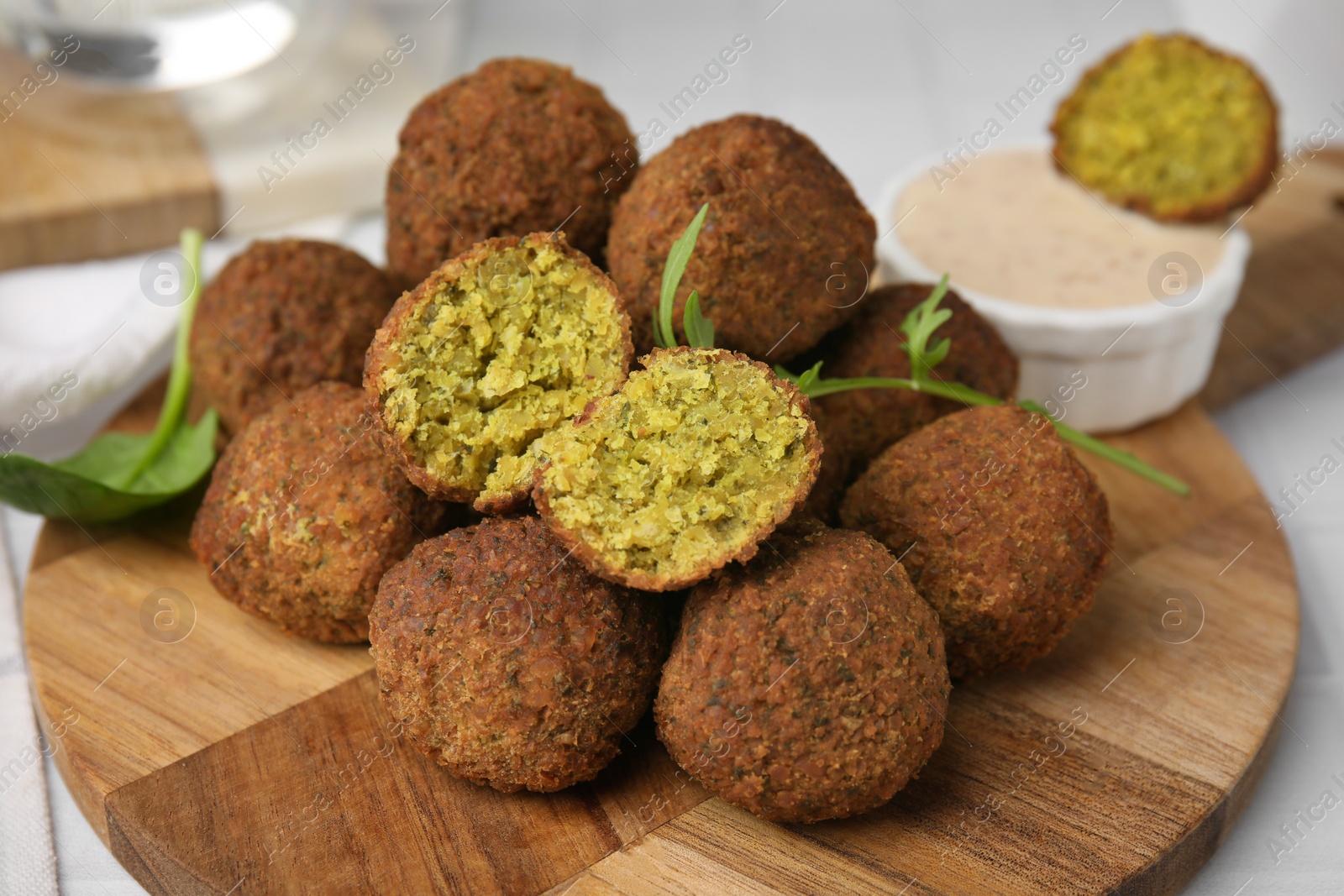 Photo of Delicious falafel balls, herbs and sauce on table, closeup