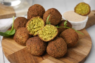 Photo of Delicious falafel balls, herbs and sauce on table, closeup