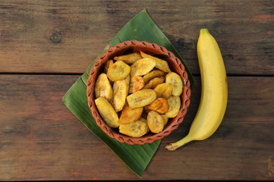 Tasty deep fried banana slices and fresh fruit on wooden table, flat lay