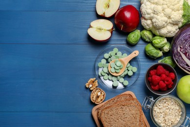 Photo of Bowl with pills, foodstuff and space for text on blue wooden table, flat lay. Prebiotic supplements