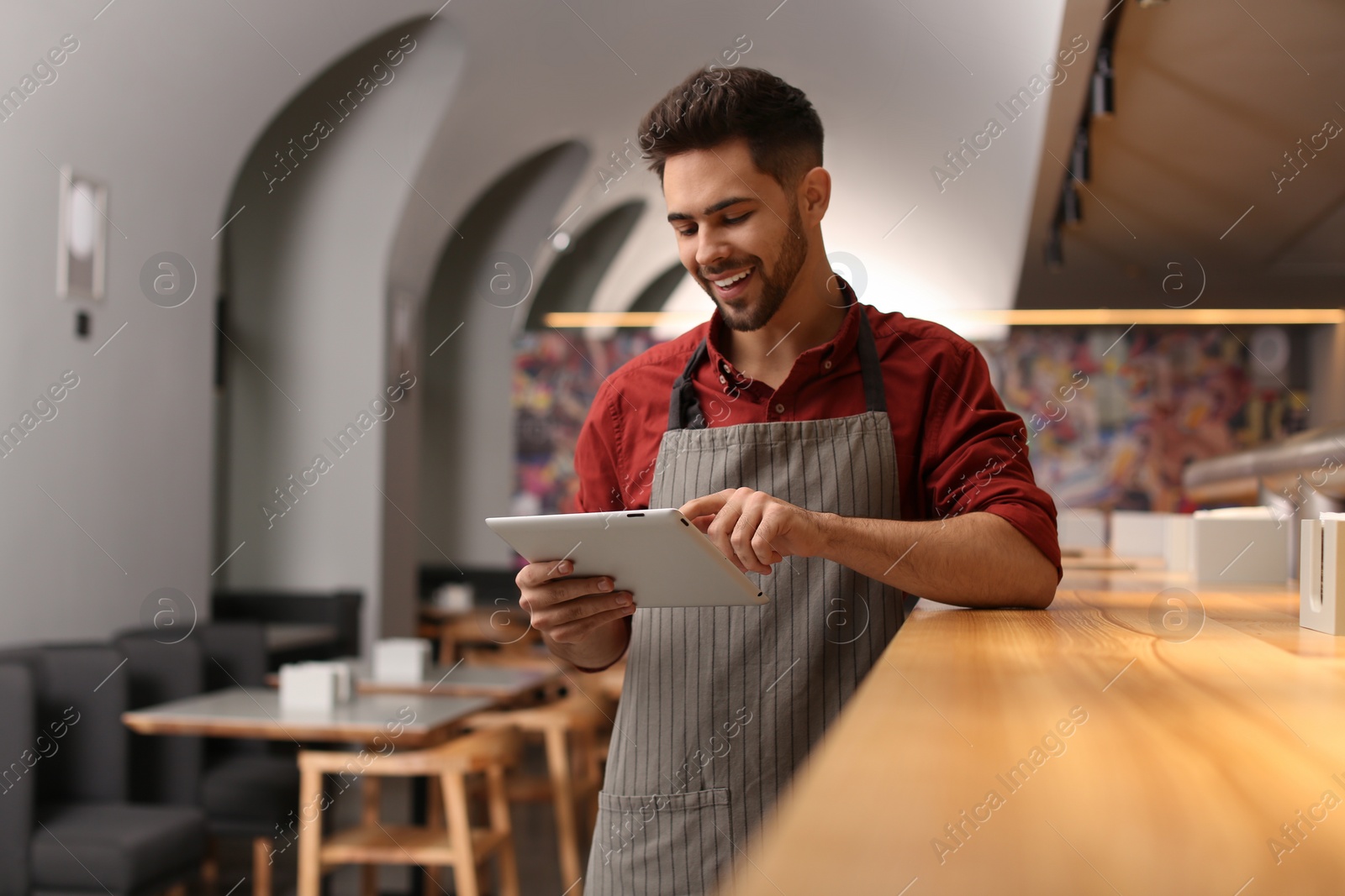 Photo of Young male business owner with tablet near counter in his cafe
