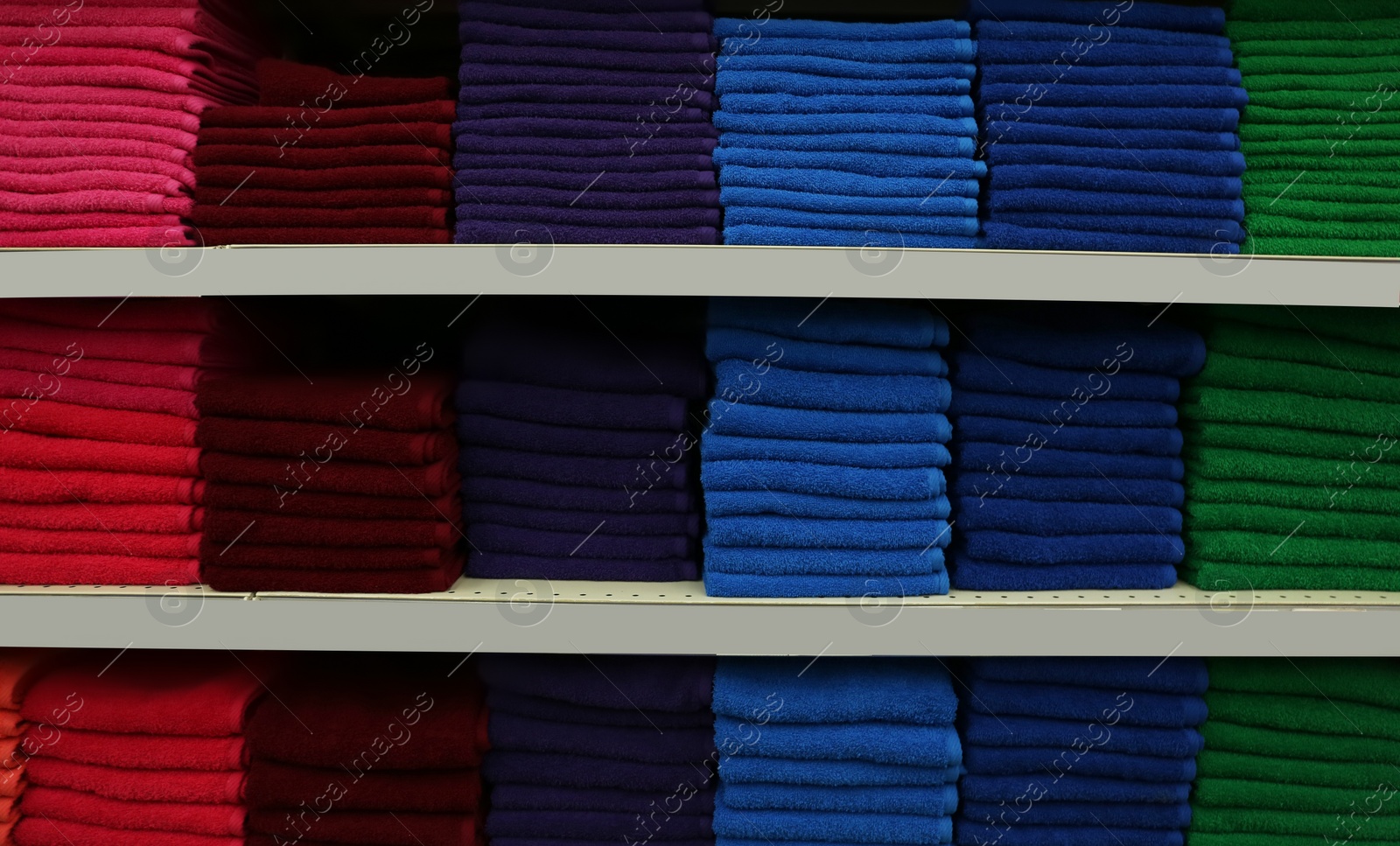 Photo of Stacks of colourful towels on store shelves