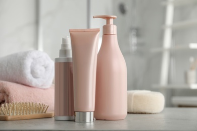 Photo of Different hair care products, towels and brush on table in bathroom