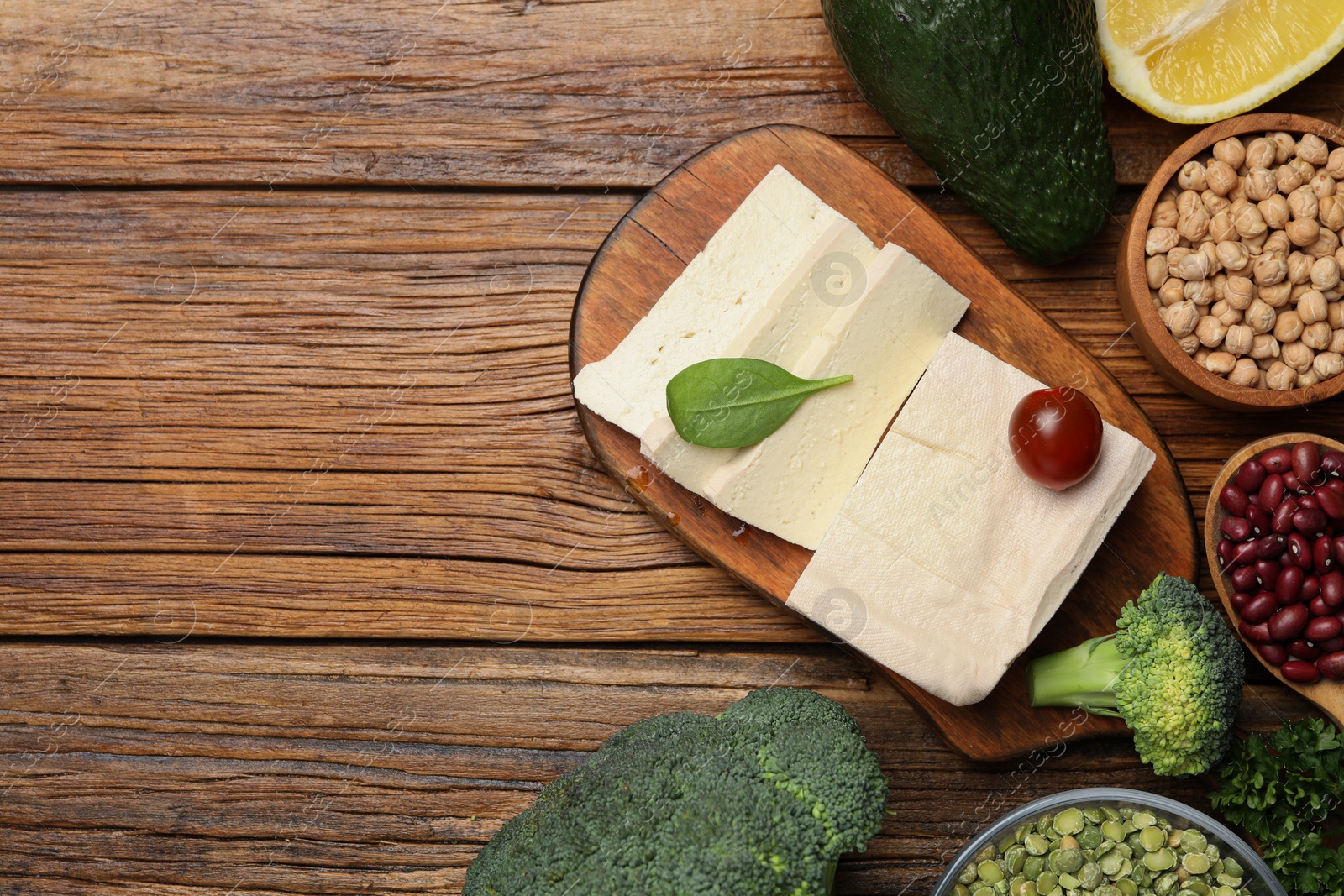 Photo of Tofu cheese and different vegetables on wooden table, flat lay with space for text. Vegan diet