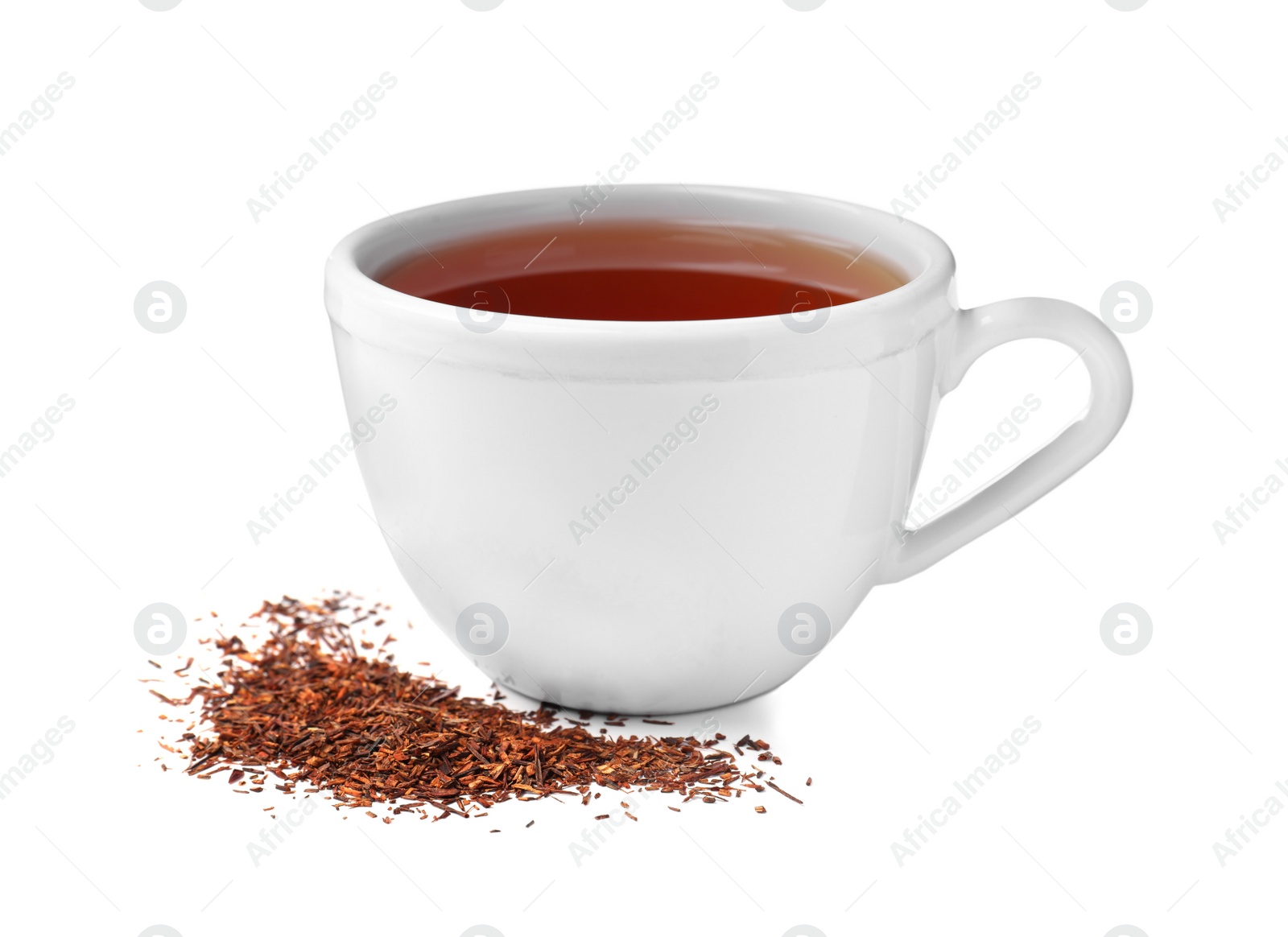 Photo of Aromatic rooibos tea in ceramic cup and scattered dry leaves on white background