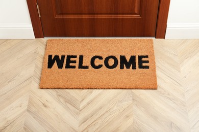 Photo of New clean brown mat with word Welcome near entrance door