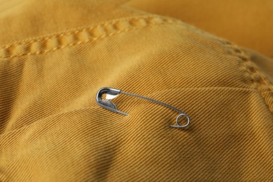 Photo of Closeup view of metal safety pin on clothing