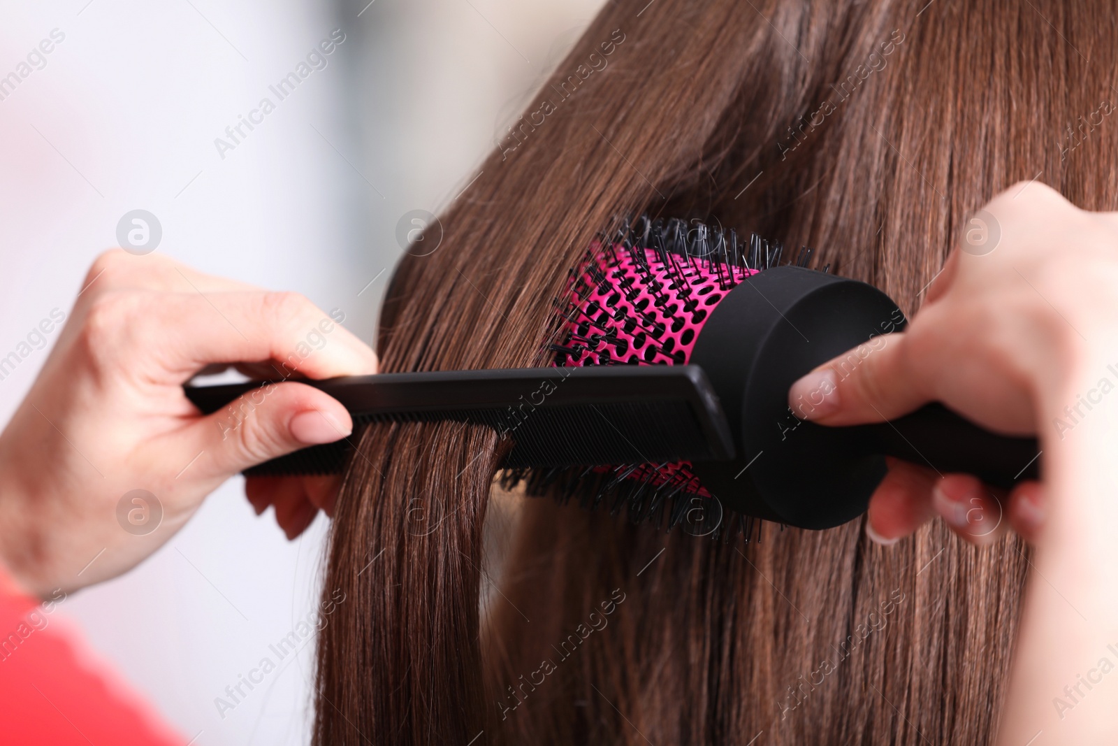 Photo of Stylist brushing woman's hair in salon, closeup