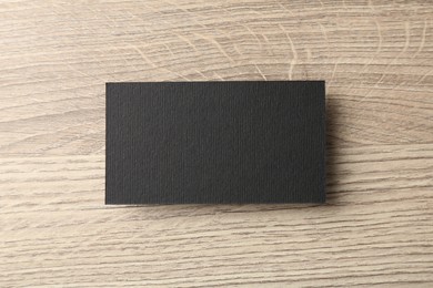 Photo of Blank black business card on wooden table, top view. Mockup for design