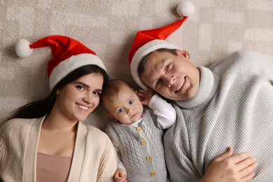 Photo of Happy couple with cute baby on floor, top view. Christmas celebration
