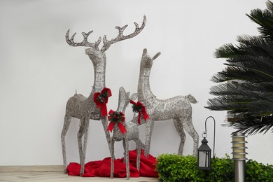 Photo of Beautiful Christmas deers near palm tree outdoors. Festive street decorations