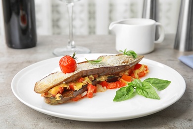 Photo of Baked eggplant with tomatoes, cheese and basil served on table