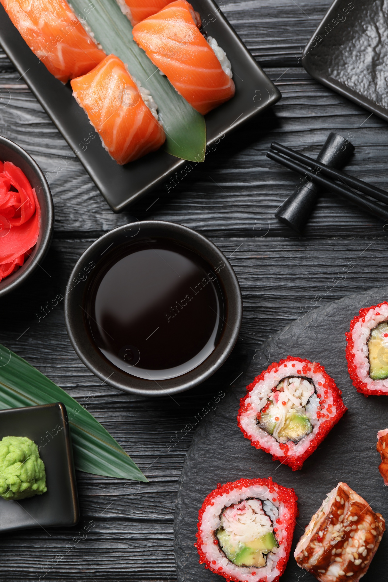Photo of Flat lay composition with different sushi rolls on black wooden table