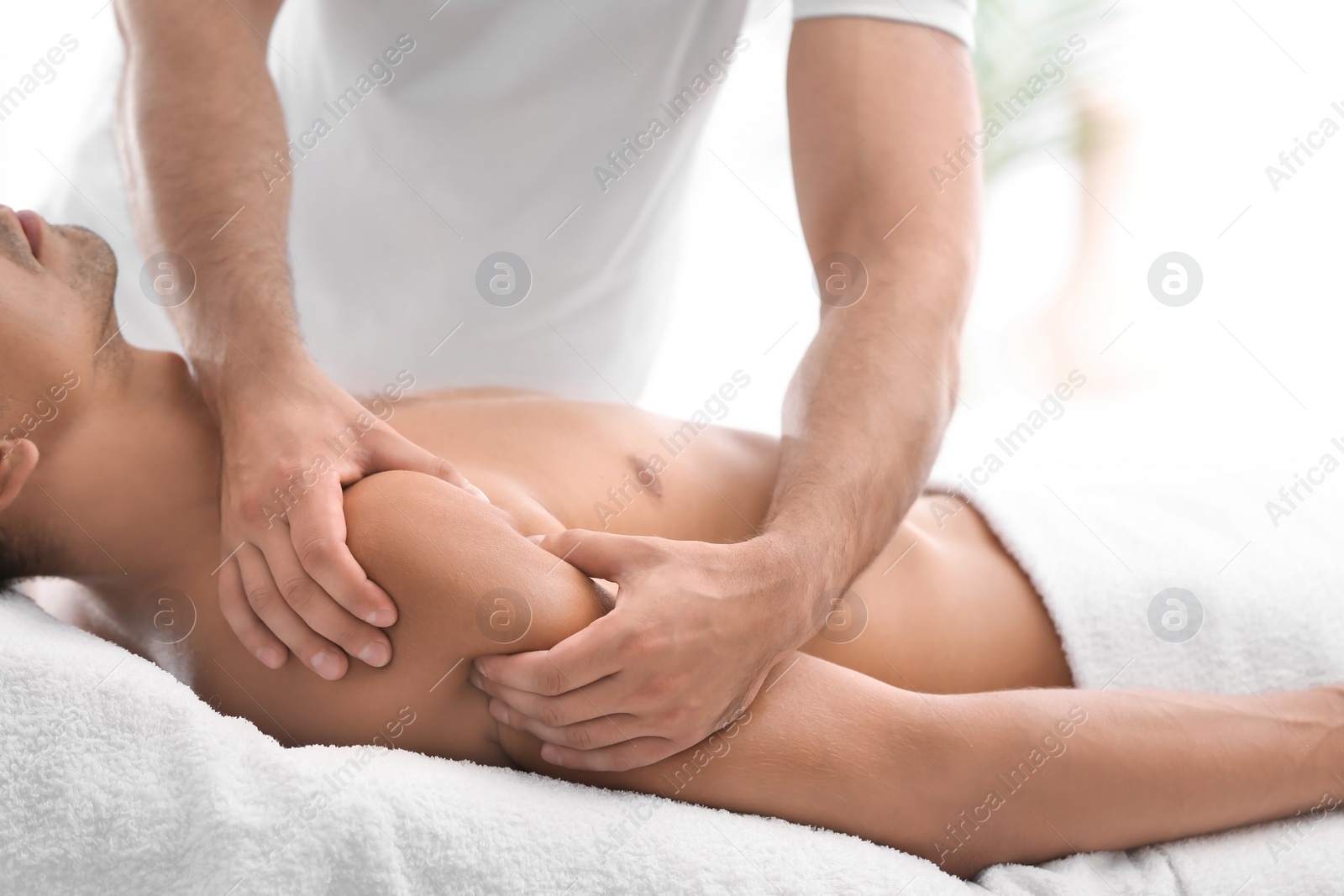 Photo of Young man receiving massage in salon, closeup