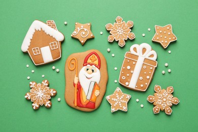 Tasty gingerbread cookies on green background, flat lay. St. Nicholas Day celebration