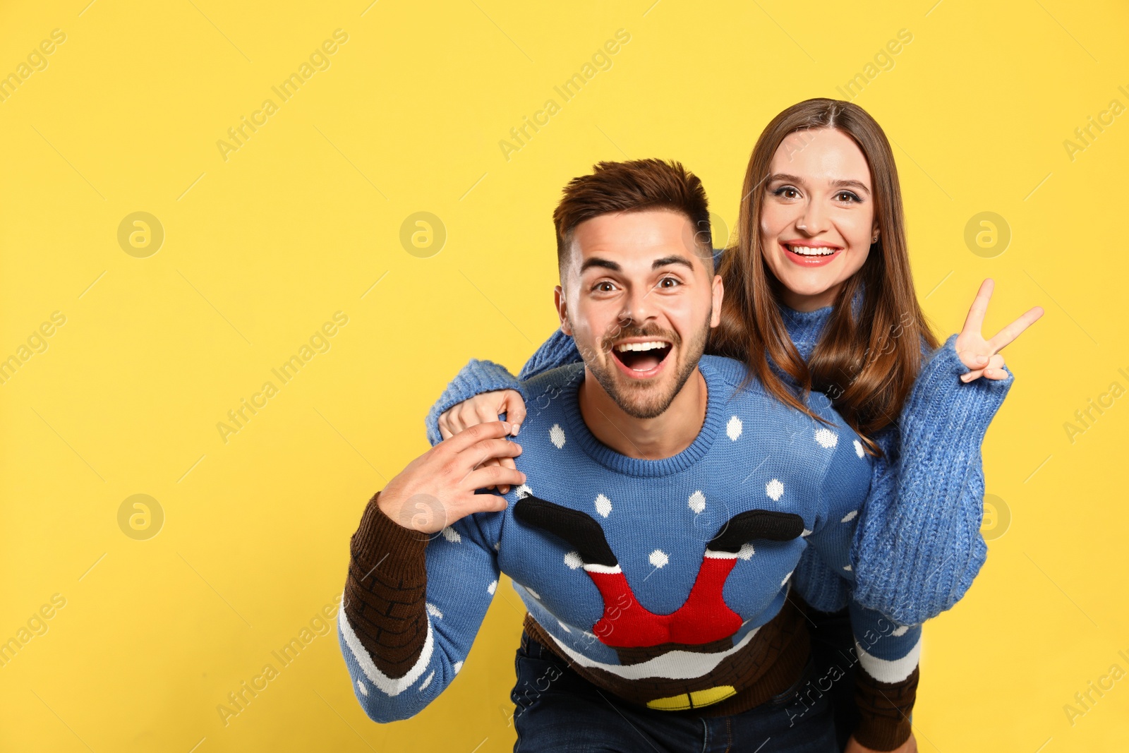 Photo of Couple wearing Christmas sweaters on yellow background