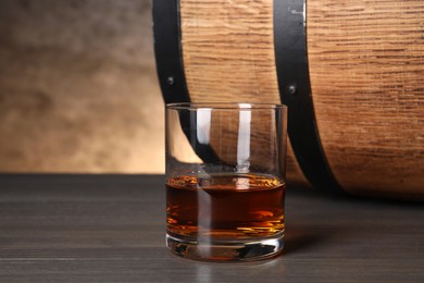Barrel and glass of tasty whiskey on wooden table