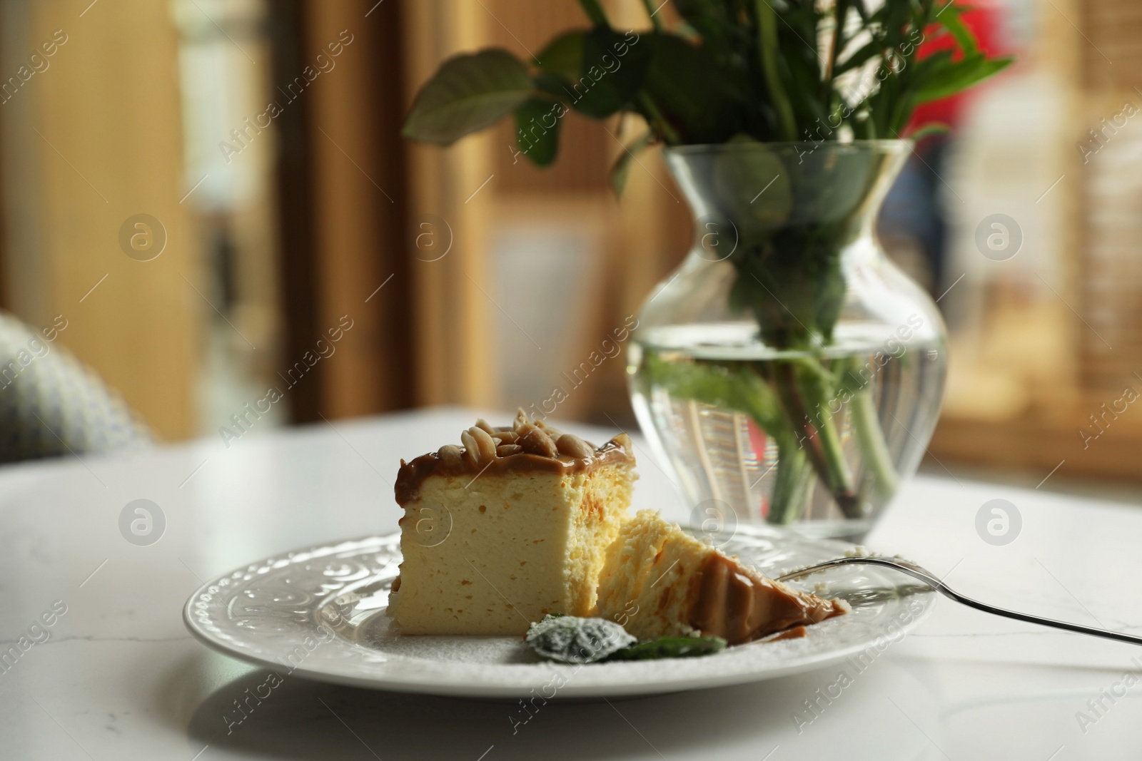 Photo of Tasty dessert and vase with flowers on white table indoors