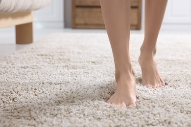 Woman walking on soft light brown carpet at home, closeup. Space for text