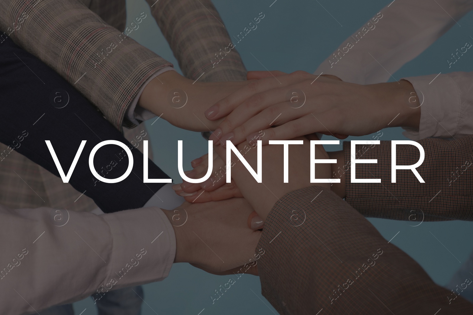 Image of Group of volunteers putting hands together on light background, closeup