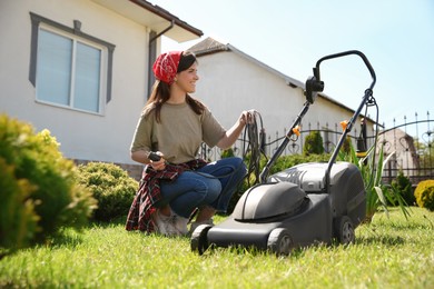 Smiling woman with modern lawn mower in garden