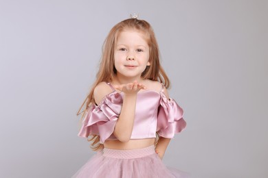 Photo of Cute girl in beautiful dress with small crown on light grey background. Little princess