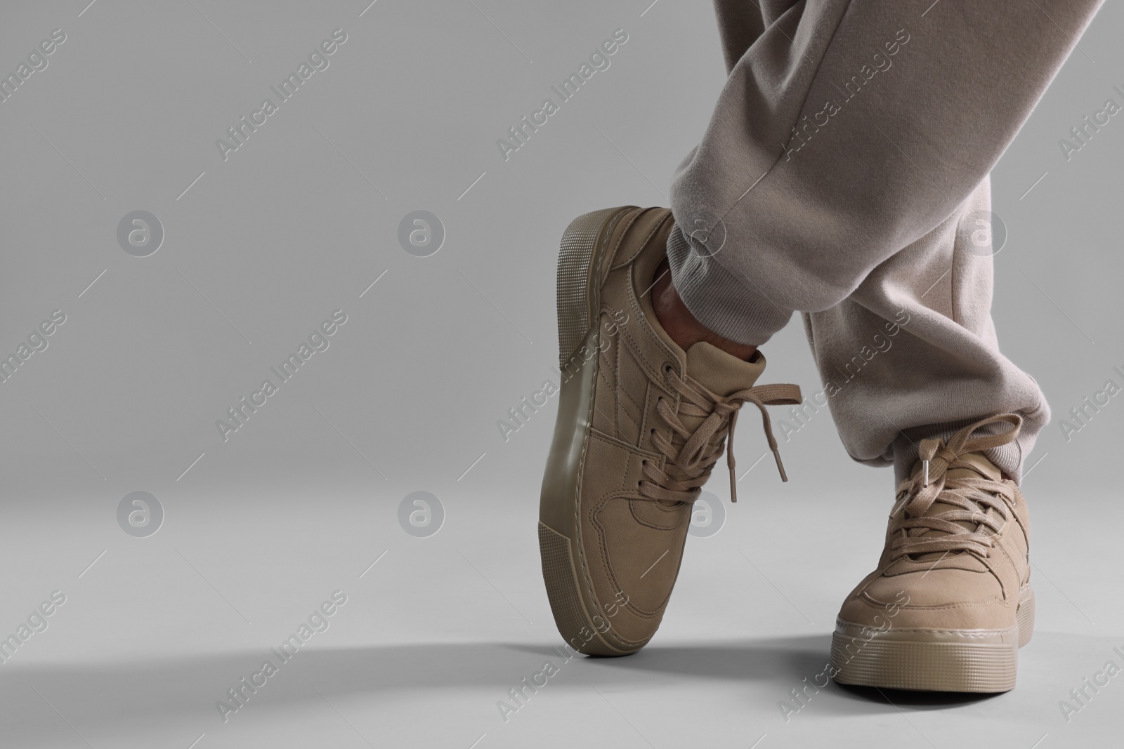 Photo of Man wearing stylish sneakers on light grey background, closeup. Space for text