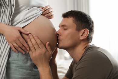 Photo of Young pregnant woman with her husband indoors, closeup