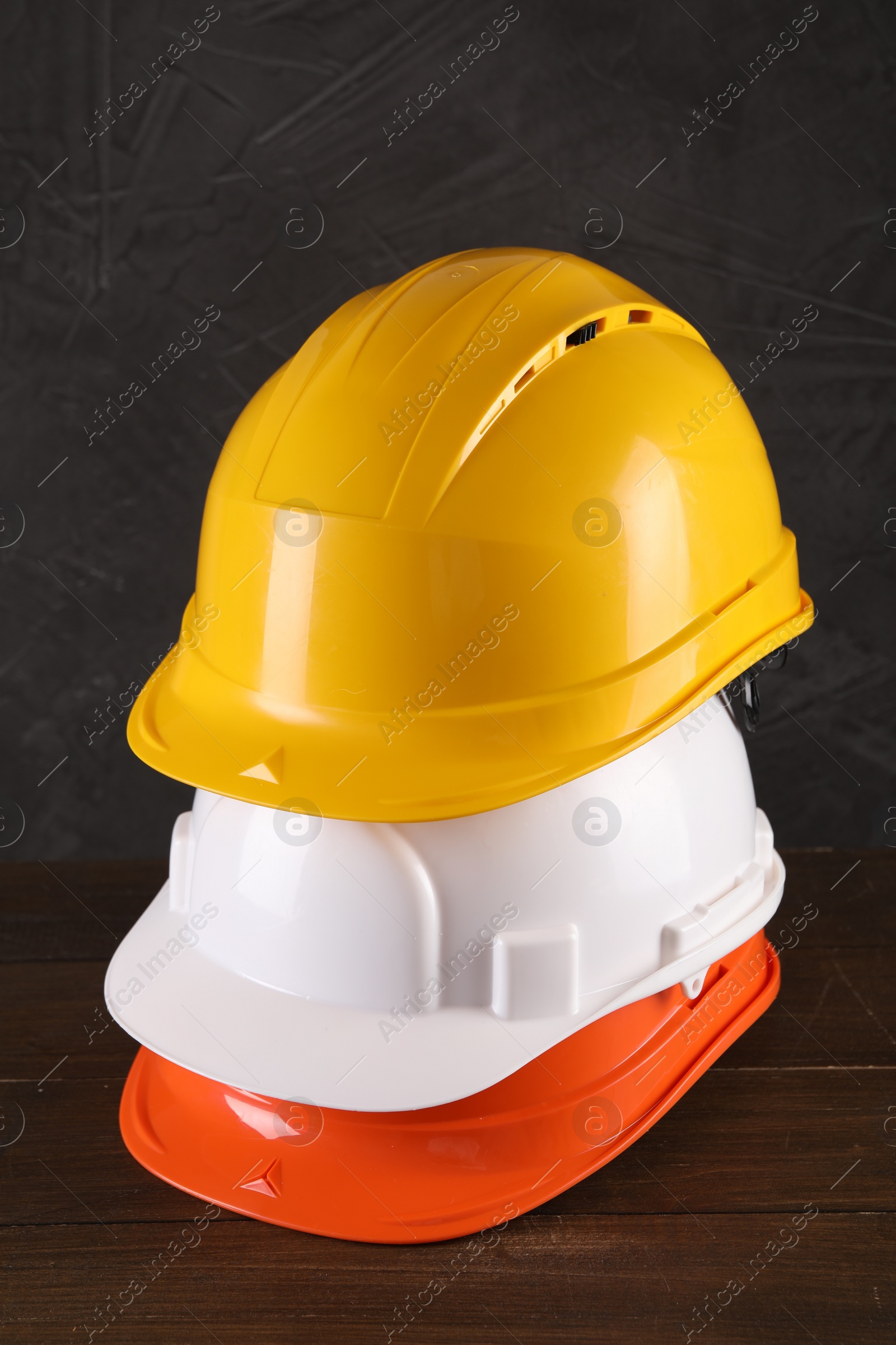 Photo of Hard hats on wooden table. Safety equipment