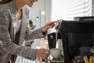 Photo of Young woman preparing fresh aromatic coffee with modern machine in office, closeup