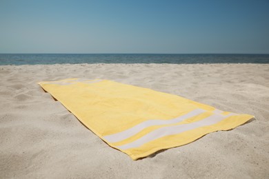 Photo of Yellow beach towel on sand near sea