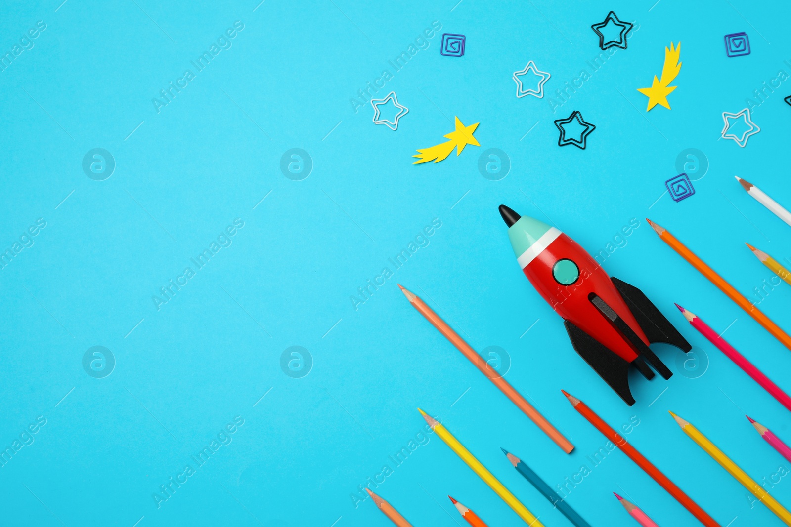 Photo of Bright toy rocket and school supplies on light blue background, flat lay. Space for text