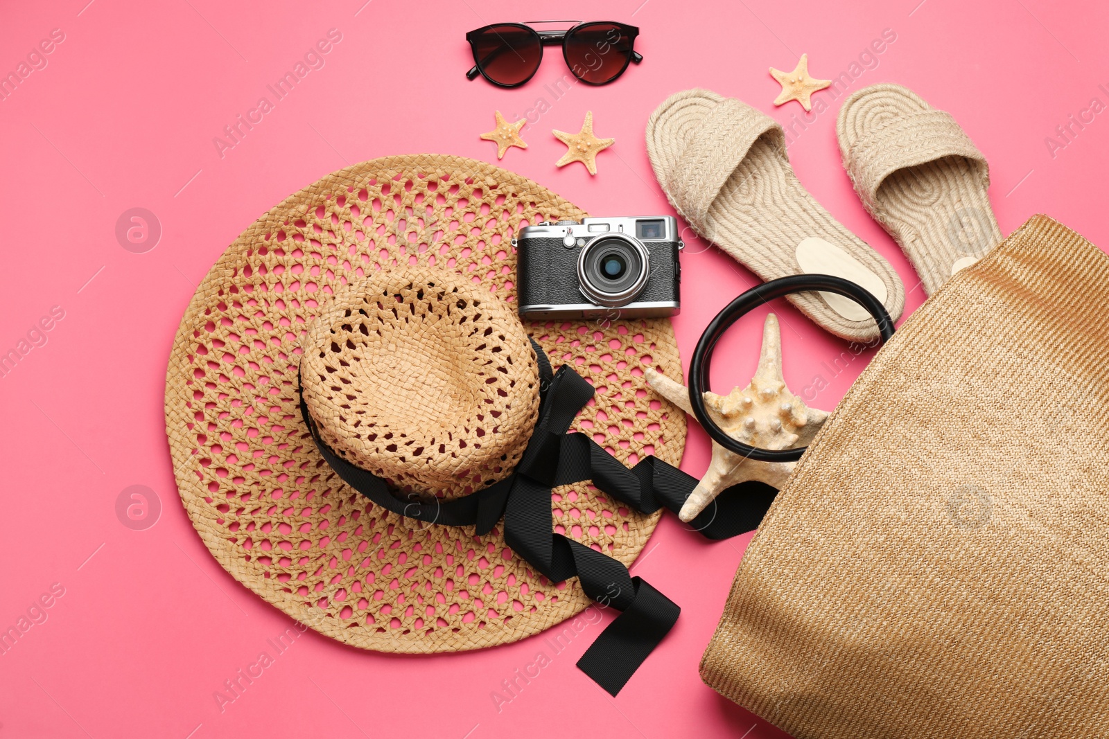 Photo of Stylish bag with beach accessories on pink background, flat lay