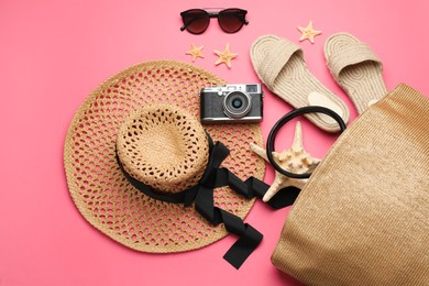 Photo of Stylish bag with beach accessories on pink background, flat lay