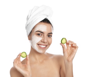 Photo of Happy young woman with organic mask on her face holding cucumber slices against white background