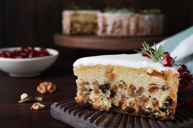 Photo of Piece of traditional homemade Christmas cake and pomegranate on wooden table, closeup