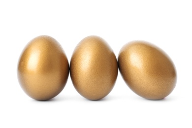 Photo of Three shiny golden eggs on white background