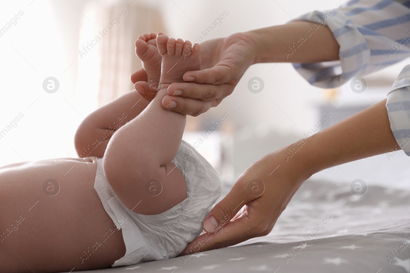 Photo of Mother changing her baby's diaper on bed, closeup