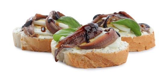 Delicious bruschettas with anchovies, eggs, basil and sauce on white background