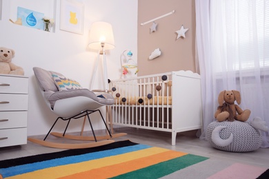 Photo of Cozy baby room interior with crib and rocking chair