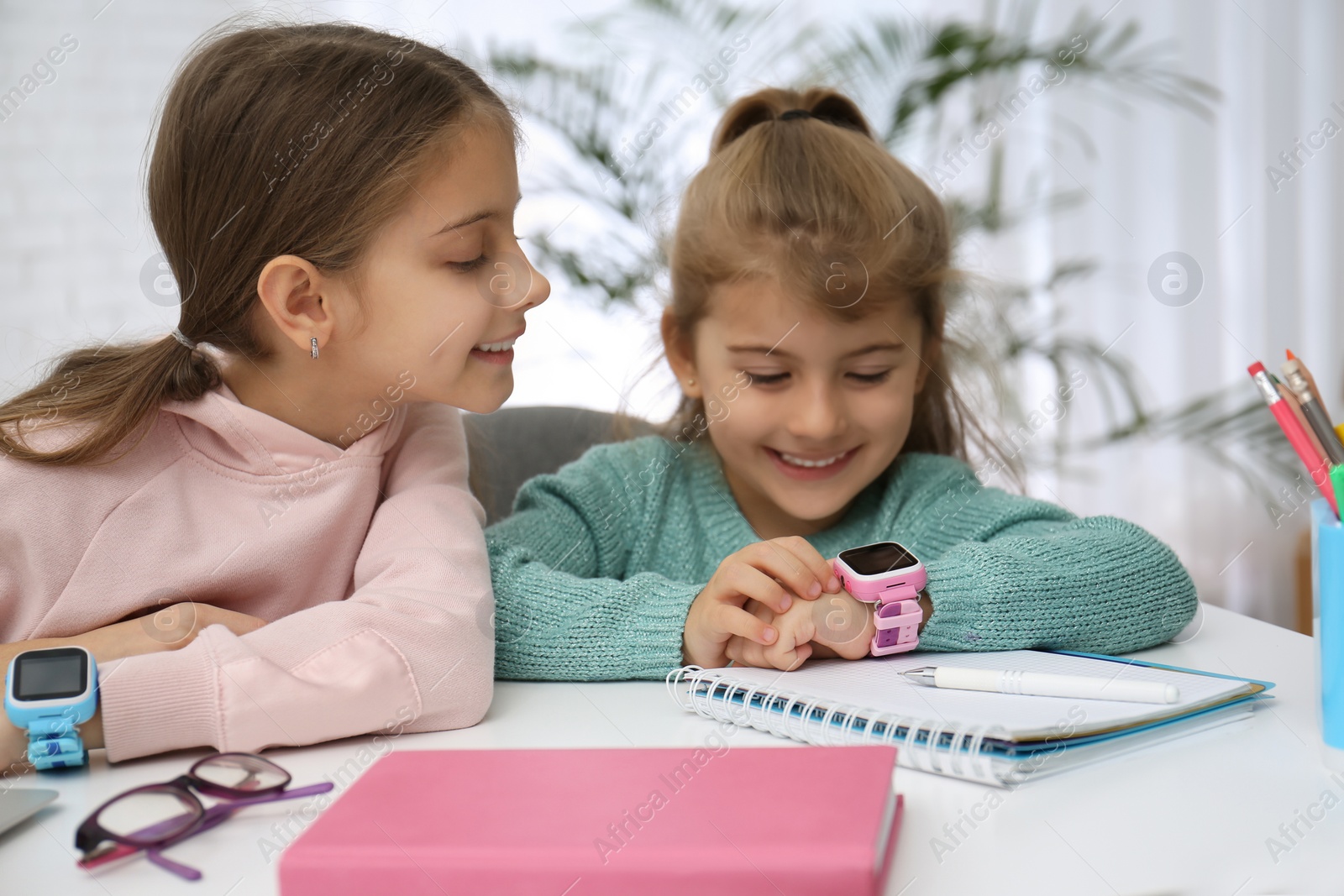 Photo of Girls with stylish smart watches at table indoors