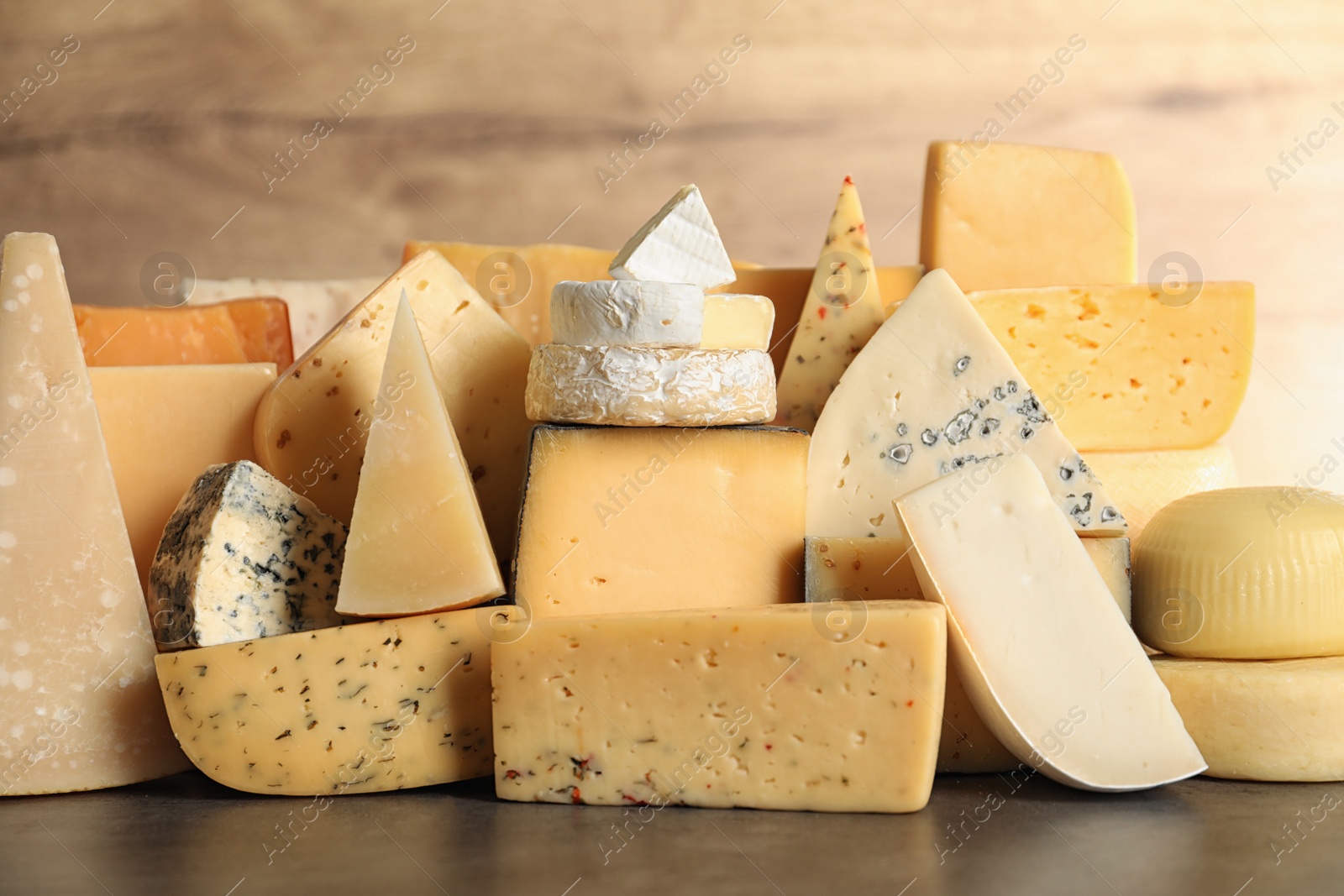 Photo of Different types of delicious cheese on table against wooden background