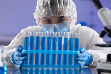 Scientist working with test tubes of light blue liquid in laboratory